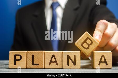 Der Geschäftsmann stellt Holzblöcke mit den Worten Plan A und B. Strategieplanung. Unternehmensleitung. Wählen Sie die richtige Lösung. Backup-Plan. Optionen an Stockfoto