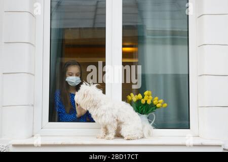 Junges Mädchen, das aus dem Fenster zu ihrem Haustier Hund schaut Stockfoto