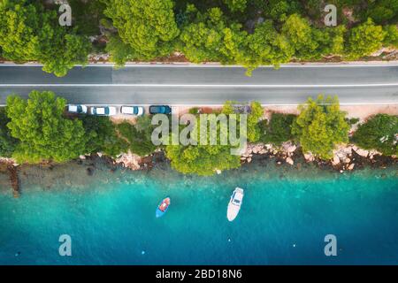 Blick auf die Straße im wunderschönen grünen Wald und auf Boote und Jacht Stockfoto