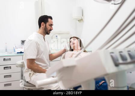 Bärtiger Zahnarztmann erklärt einem weiblichen Patienten das Verfahren Stockfoto