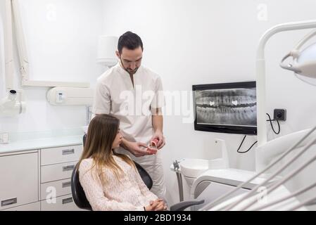 Arzt zeigt dem Patienten, wie saubere Zähne an der Zahnprobe sind Stockfoto