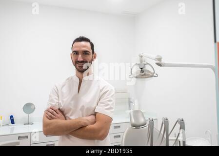 Porträt eines lächelnden männlichen Arztes, der in einer Zahnarztstube posiert Stockfoto