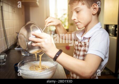 Kleines süßes Dessert zum Kochen von Jungen in der Küche. Familiärer Kochhintergrund. Stockfoto