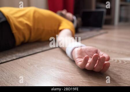 Junger Mann meditiert auf einem Boden und liegt in Shavasana Pose in seinem Wohnzimmer. Stockfoto