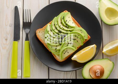 Avocado Toast mit Zutaten und Besteck Stockfoto