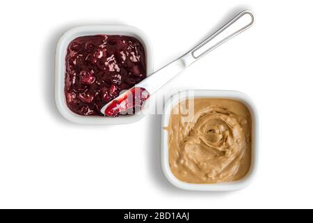 Erdnussbutter und Erdbeergelee gefüllte Schalen auf weißem Hintergrund mit Erdbeermarmelade beschichteten Spreizmesser isoliert Stockfoto