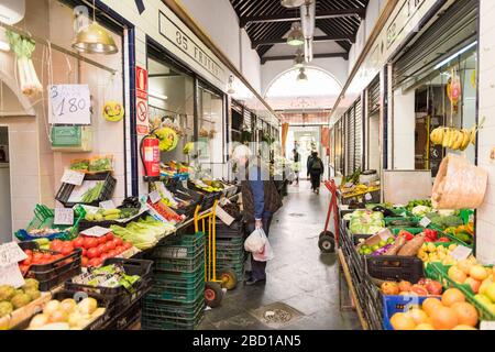 Ein Kunde, der die Produkte auf einem Obst- und Gemüsestall am Mercado de Triana, dem Lebensmittelmarkt in Triana Sevilla Spanien, betrachtet Stockfoto