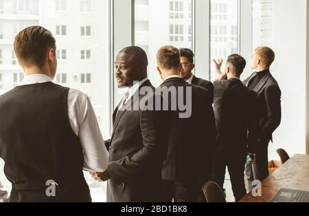 Dialog zweier Geschäftsleute in Anzügen, die in einem Büro zusammenarbeiten und miteinander kommunizieren. Geschäftsleute und Manager in einem Meeting. Stockfoto