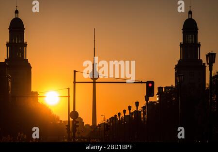 Berlin, Deutschland. April 2020. Die Sonne untergeht hinter dem Fernsehturm, über die Karl-Marx-Allee und hinter den Wohntürmen am Frankfurter Tor. Kredit: Soeren Stache / Zentralbild / ZB / dpa / Alamy Live News Stockfoto
