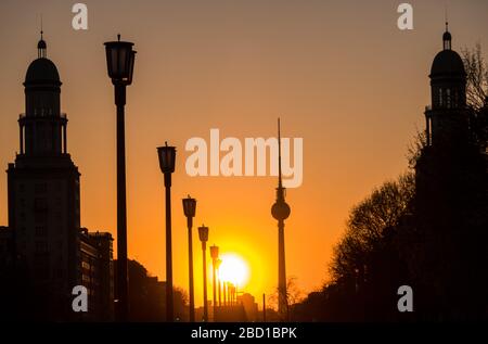 Berlin, Deutschland. April 2020. Die Sonne untergeht hinter dem Fernsehturm, über die Karl-Marx-Allee und hinter den Wohntürmen am Frankfurter Tor. Kredit: Soeren Stache / Zentralbild / ZB / dpa / Alamy Live News Stockfoto