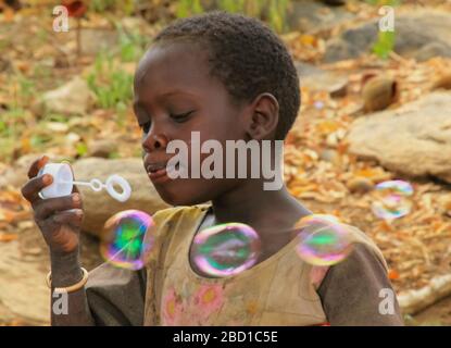 Afrika, Tansania, Lake Eyasi, junges männliches Hadza-Kind spielt mit Seifenblasen. Hadza, oder Hadzabe, sind eine indigene Ethnie im nordzentralen Tanza Stockfoto