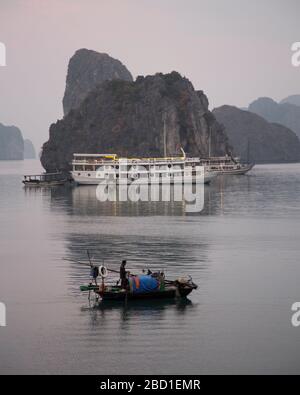Ein Blick am frühen Morgen auf Ha Long Bay mit lokalen Fischerbooten und Tour Boote zwischen den Kalksteinklippen Formationen, Stockfoto