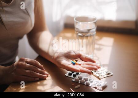 Nahaufnahme der Hände der Frau halten Pillen. Hand mit Pillen und Glas Wasser. Störfestigkeit. Vitamine Stockfoto