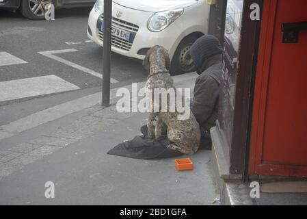 Obdachloser, der mit seinem Hund vor einem Geschäft sitzt, Paris, pasakdek Stockfoto