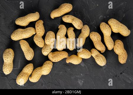 Erdnüsse auf dunklem Hintergrund. Erdnüsse in einer Schale. Gesundes Essen. Top-Ansichten, Nahaufnahme Stockfoto