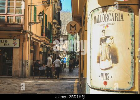 Palma, Mallorca / Spanien - 26. März 2018: Touristen schlendern an einem sonnigen Tag in die Einkaufsstraße. Vintage-Werbung im Vorderteil Stockfoto