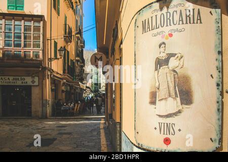 Palma, Mallorca / Spanien - 26. März 2018: Touristen schlendern an einem sonnigen Tag in die Einkaufsstraße. Vintage-Werbung im Vorderteil Stockfoto