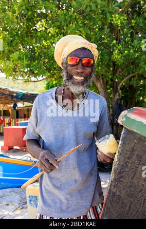 Grinning man repariert Boot, bunte Saltwhistle Bay, Mayreau, Grenadinen, St. Vincent und die Grenadinen, Windward Islands, Karibik Stockfoto