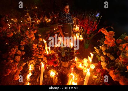 Zapotec-Frau hält Kerze unter den Gräbern, die mit Marigolden, Atzompa, Oaxaca, Mexiko, Nordamerika verziert sind Stockfoto