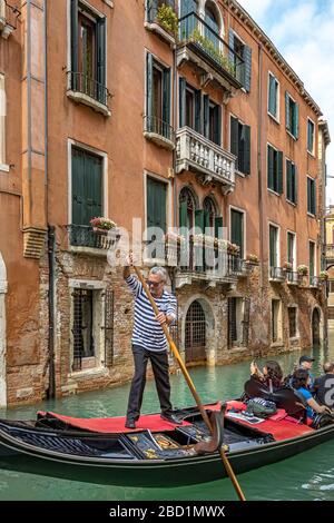 Ein Gondolier steuert seine Gondel mit seinem Ruder entlang des Rio de San Moise, einem Kanal in Venedig, Italien Stockfoto