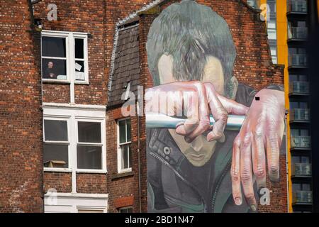 Manchester, Großbritannien. April 2020. Am Montag, den 6. April 2020, blickt ein Mann aus seinem Fenster über einige Straßenkunst in der Great Ancoats Street im Stadtzentrum von Manchester. (Credit: Pat Scaasi/MI News) Credit: MI News & Sport /Alamy Live News Stockfoto