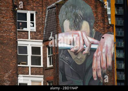 Manchester, Großbritannien. April 2020. Am Montag, den 6. April 2020, blickt ein Mann aus seinem Fenster über einige Straßenkunst in der Great Ancoats Street im Stadtzentrum von Manchester. (Credit: Pat Scaasi/MI News) Credit: MI News & Sport /Alamy Live News Stockfoto