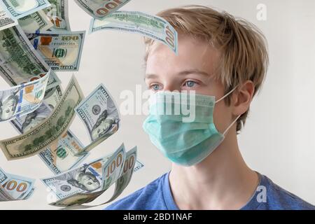 Junger Mann in einer medizinischen Maske gegen die Infektion mit Coronavirus und Geld, das Geld fällt, Geld in bar Stockfoto