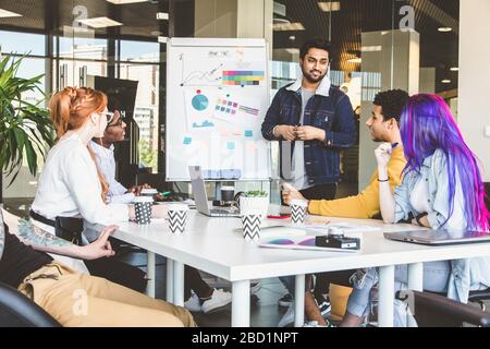 Gruppe von Führungskräften aus mehreren ethnischen Gruppen, die während eines Meetings diskutieren. Business man und Frau sitzen am Tisch im Büro und lächeln. Ein Team junger Leute Stockfoto