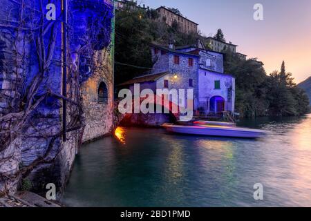 Boot in Bewegung unter der beleuchteten Nesso-Brücke, dem Comer See, der Lombardei, den italienischen Seen, Italien, Europa Stockfoto