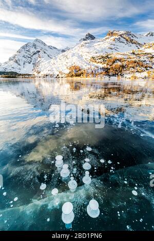 Methan sprudelt in der eisigen Oberfläche von Silsersee mit schneereichen Gipfel, Silsee, Engadiner Tal, Graubünden, Schweizer Alpen, Schweiz, Europa Stockfoto