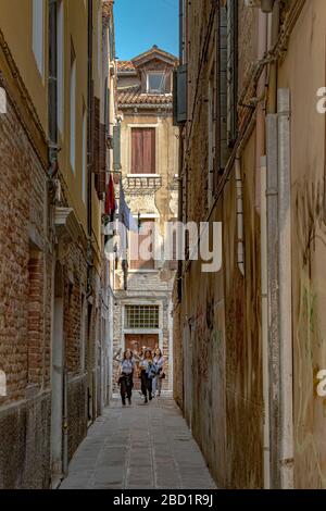 Kinder laufen die Calle de Mezo De La Vida entlang, eine enge Gasse am Rio Terà Kanal im Dorsoduro Viertel von Venedig, Italien Stockfoto