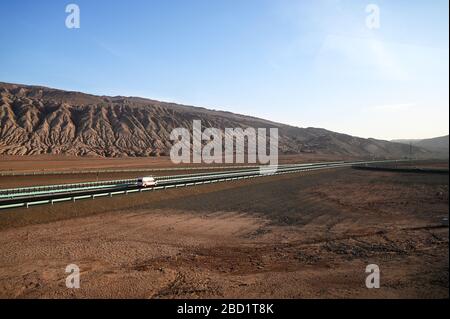 Polizeifahrzeug, das auf der menschenleeren Seidenstraße in der Wüste Gobi bei Turfan, Xinjiang, China, Asien fährt Stockfoto