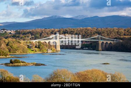 Die Menai Suspension Bridge über die Menai Strait mit den Bergen von Snowdonia im Hintergrund, Anglesey Stockfoto