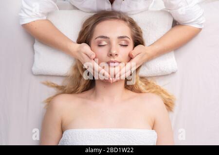 Nahaufnahme eines Porträts einer Energietherapie mit einem Heiler, der einen Kopf der jungen Frau hält. Stockfoto