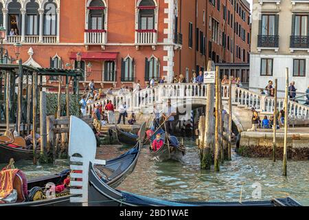 Leute, die auf einer Kanalbrücke stehen und Touristen beobachten, die Gondelfahrten vor dem Hotel Hotel Danieli am Canal Grande, Venedig, Italien, machen Stockfoto