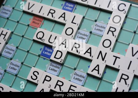 Coronavirus verwandte Wörter, die auf einem Scrabble Board ausgeschrieben sind. Konzeptbild für redaktionelle Kovid-19-bezogene Geschichten. Mit selektivem Fokus. Stockfoto