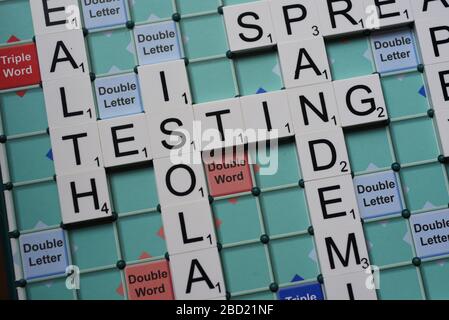 Coronavirus verwandte Wörter, die auf einem Scrabble Board ausgeschrieben sind. Konzeptbild für redaktionelle Kovid-19-bezogene Geschichten. Mit selektivem Fokus. Stockfoto