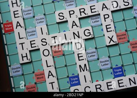 Coronavirus verwandte Wörter, die auf einem Scrabble Board ausgeschrieben sind. Konzeptbild für redaktionelle Kovid-19-bezogene Geschichten. Mit selektivem Fokus. Stockfoto