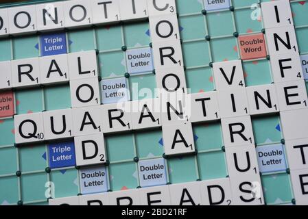 Coronavirus verwandte Wörter, die auf einem Scrabble Board ausgeschrieben sind. Konzeptbild für redaktionelle Kovid-19-bezogene Geschichten. Mit selektivem Fokus. Stockfoto