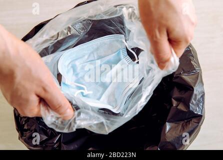 Wegwerfen einer medizinischen Gesichtsmaske für Einmalgebrauch. Packen Sie es in einer Plastiktüte, bevor Sie es in den Müll werfen, um zu verhindern, dass sich der Virus aus der Maske t ausbreitet Stockfoto