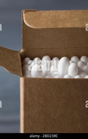 Nahaufnahme der Bambusstäbchen in der Öko-Papierbox auf blauem Hintergrund. Umweltfreundliches und abfallarrestes Konzept. Selektiver Fokus-Kopierraum Stockfoto