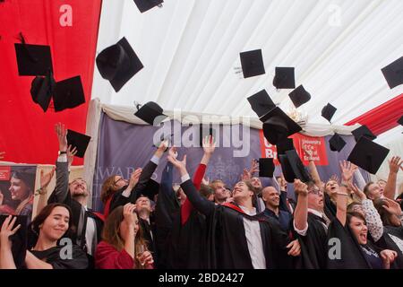 Studenten feiern den Abschluss, indem sie ihre Mörtelbretter in die Luft werfen Stockfoto