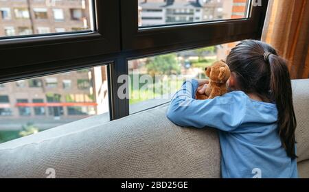 Unerkennbares trauriges Mädchen mit Blick auf das Fenster Stockfoto