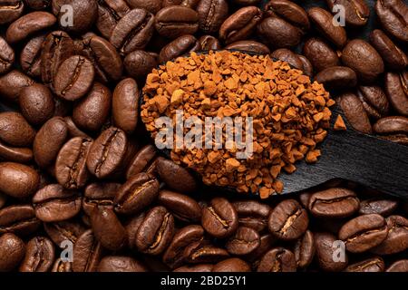 Hintergrund von Kaffeebohnen und Instantkaffee auf schwarzem Holzlöffel. Draufsicht. Stockfoto