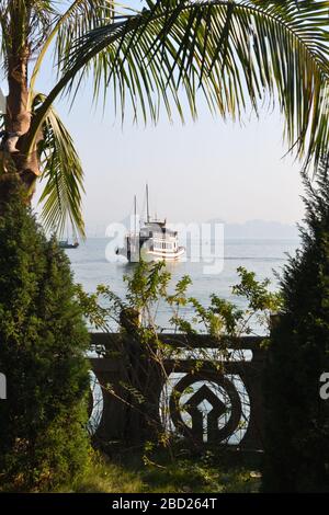 Eine chinesische Schrotfähre in der berühmten ha Long Bay der UNESCO, umrahmt mit Palmen und dekorativer Wand in Vietnam, Asien Stockfoto