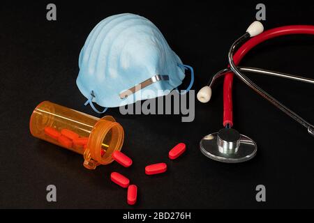 Medizinische Maske und Stethoskop mit roter Tablette auf Schwarz Stockfoto