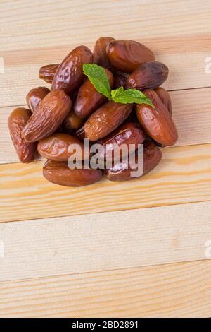 Nahwärme von getrockneten Datteln Palmfrüchte mit minzgrünem Blatt isoliert auf Holzfarmtisch, ramadan Concept Stockfoto