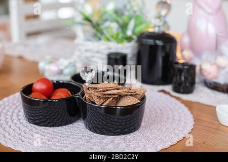 Schwarze Teller mit Schnäbeln und roten Tomaten stehen auf dem Tisch Stockfoto