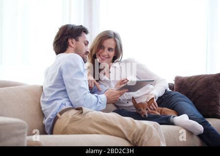 Paare zu Hause mit Hund auf digitale Tablette Stockfoto