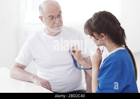Arzt, der den männlichen Patienten im Krankenhaus untersucht, Herzschlag hören, Kardiologie Stockfoto